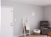 Thumbnail 14 of 17 - A white door is on the left of a room with a ladder, a chair, and a clock on the wall.