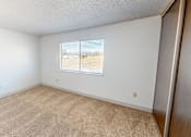 Thumbnail 10 of 28 - A room with a carpeted floor and a window with blinds.