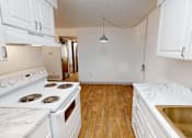 Thumbnail 8 of 28 - A kitchen with a white stove top oven and white cabinets.