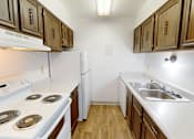 Thumbnail 11 of 28 - A kitchen with white appliances and wooden cabinets.