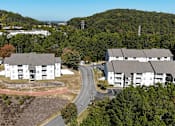 Thumbnail 24 of 27 - an aerial view of an apartment complex with a road and trees