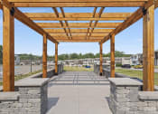 Thumbnail 22 of 34 - a pergola with stone pillars and a parking lot in the background
