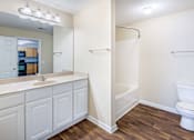 Thumbnail 13 of 33 - Primary bathroom with bright vanity and wood style flooring