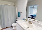 Thumbnail 11 of 33 - A bathroom with a white sink, toilet, and shower curtain.