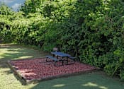 Thumbnail 21 of 33 - A picnic table is on a red gravel area in a green grassy area.