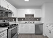 Thumbnail 1 of 33 - Apartment kitchen with white cabinets and a black stove top oven