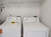 Thumbnail 15 of 33 - Two white front loading washing machines in a laundry room.