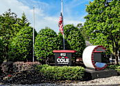 Thumbnail 30 of 33 - A sign for Cole Apartments is in front of a green hedge and a flag pole.