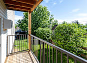 Thumbnail 10 of 20 - A balcony with a tile floor and a metal railing overlooks a yard.