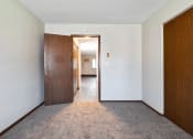 Thumbnail 4 of 18 - a bedroom with a door to a hallway and a carpeted floor