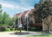 Thumbnail 26 of 31 - a building with two flag poles and a sign in front of it