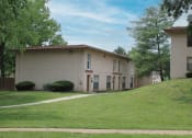 Thumbnail 25 of 31 - the front of a tan building with a green lawn