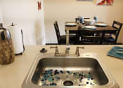 Thumbnail 9 of 31 - a sink with marbles in it and a dining room table and chairs in the background