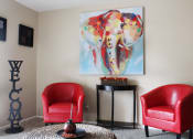 Thumbnail 2 of 31 - a living room with a large painting of an elephant on the wall and two red chairs
