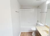 Thumbnail 24 of 36 - A white bathroom with a toilet, sink, and shower.
