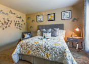 Thumbnail 17 of 36 - A bedroom with a bed, nightstand, and wall decorations.