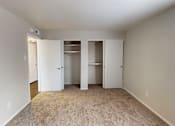 Thumbnail 20 of 36 - A room with white walls and a carpeted floor with three open doors.
