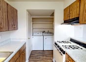 Thumbnail 12 of 36 - A kitchen with a white stove top oven and a white dishwasher.
