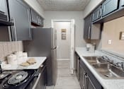 Thumbnail 6 of 30 - A kitchen with a stove top oven, a refrigerator, and a sink.