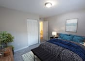 Thumbnail 7 of 11 - A bedroom with a bed, nightstand, and lamp.