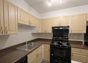 Thumbnail 3 of 11 - A kitchen with a black oven and brown countertops.
