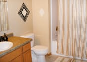 Thumbnail 11 of 19 - A bathroom with a toilet, sink, and shower curtain.