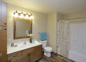 Thumbnail 13 of 19 - A bathroom with a toilet, sink, mirror, and shower.