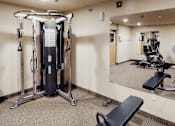 Thumbnail 14 of 19 - A gym with a mirror, weights, and a leg press machine.