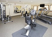 Thumbnail 15 of 19 - A gym with a treadmill, weights, and exercise equipment.