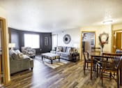 Thumbnail 6 of 19 - A living room with a grey couch and a wooden floor.