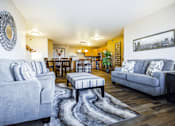 Thumbnail 8 of 19 - A living room with grey couches and a patterned rug.