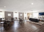 Thumbnail 14 of 32 - A living room with a grey couch, a round table, and chairs.