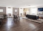 Thumbnail 15 of 32 - A living room with a grey couch, a television, and a dining table with chairs.