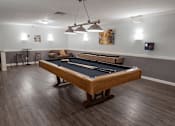 Thumbnail 16 of 32 - A pool table in a room with a light hanging from the ceiling.