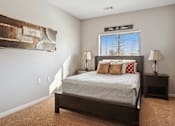 Thumbnail 7 of 24 - A bedroom with a bed, two lamps, and a painting on the wall.