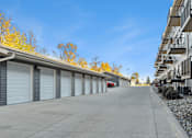 Thumbnail 20 of 24 - A row of garage doors in front of a building with a red car parked in the middle.