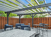 Thumbnail 21 of 24 - A patio with a table and chairs under a roof.