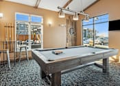 Thumbnail 9 of 24 - A pool table in a room with a view of the parking lot outside.