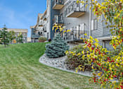 Thumbnail 24 of 24 - A grey apartment building with a green lawn in front.