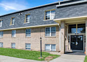 Thumbnail 26 of 27 - A brick building with a black door and windows.