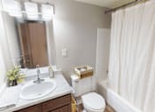 Thumbnail 5 of 30 - A white bathroom with a sink, toilet, and shower.