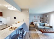 Thumbnail 2 of 30 - A kitchen with a bar area and a living room.