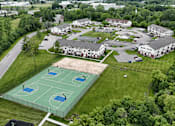 Thumbnail 21 of 30 - A basketball court is surrounded by a fence and is located in a grassy area.
