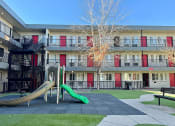 Thumbnail 22 of 28 - a playground with a slide in front of an apartment building