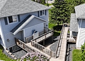 Thumbnail 22 of 34 - A house with a grey roof and a deck with a railing.