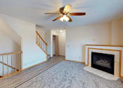 Thumbnail 1 of 34 - A living room with a fireplace and a ceiling fan.