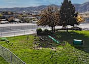 Thumbnail 19 of 30 - A park with a green trash can and a green bench.