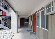 Thumbnail 26 of 30 - A long hallway with red doors and a metal staircase.