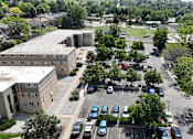 Thumbnail 29 of 30 - A parking lot with cars and a building in the background.
