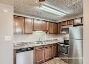 Thumbnail 3 of 20 - A kitchen with brown cabinets and stainless steel appliances.